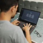 Man using a laptop with ChatGPT open while researching ai anti cheat reddit discussions indoors